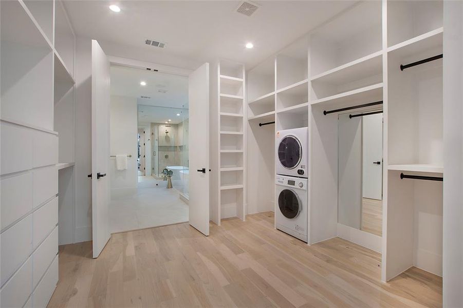 Laundry area featuring a barn door, stacked washer and dryer, and light hardwood / wood-style floors