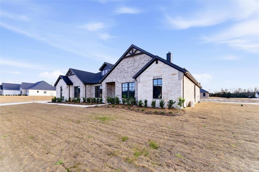 French country style house with a front lawn, a chimney, and stone siding