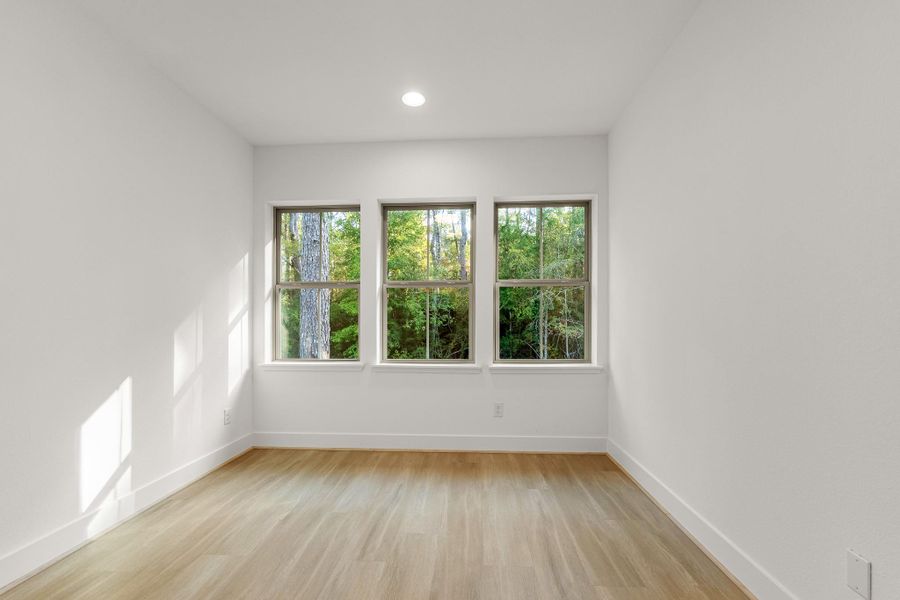 Bright room with large windows offering a view of lush greenery, featuring clean white walls and light wood flooring. Ideal for a home office or cozy bedroom. Bright room with large windows offering a view of lush greenery, featuring clean white walls and light wood flooring. Ideal for a home office or cozy bedroom.