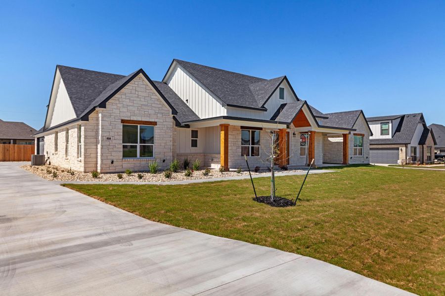 Modern inspired farmhouse with stone siding, a front yard, covered porch, board and batten siding, and a shingled roof Modern inspired farmhouse with stone siding, a front yard, covered porch, board and batten siding, and a shingled roof