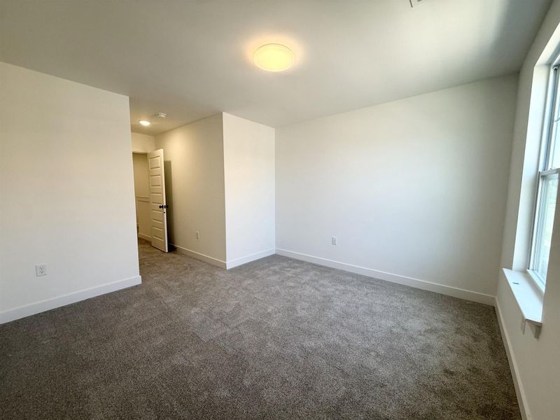 Unfurnished room featuring dark colored carpet and baseboards