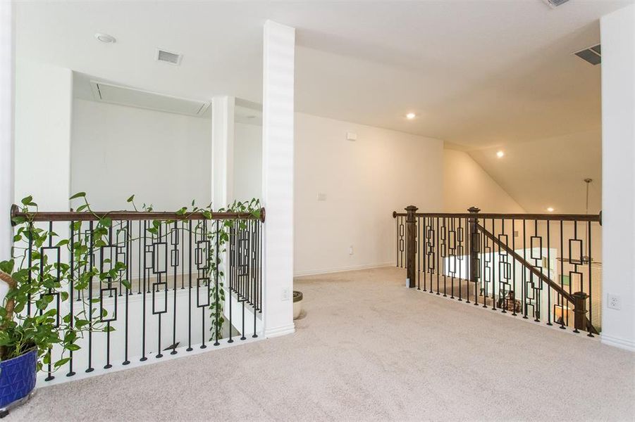 Hallway with light colored carpet and vaulted ceiling