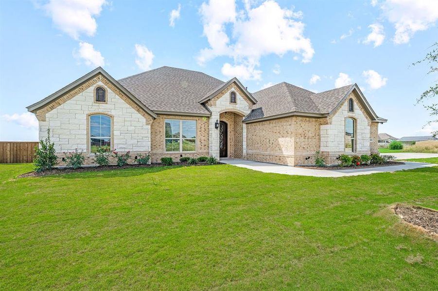French country inspired facade with stone siding, brick siding, and roof with shingles