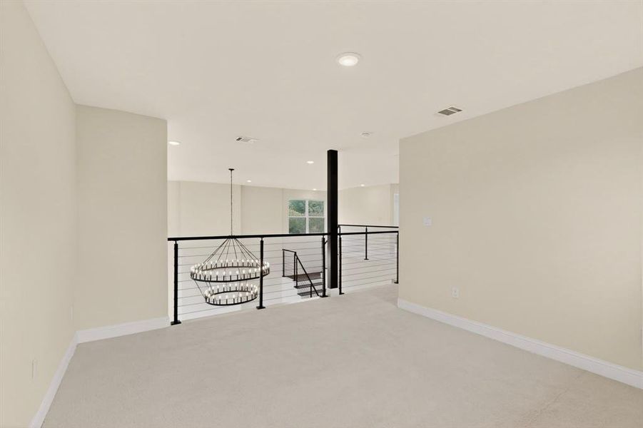 Upper-level landing featuring neutral carpeting, recessed ceiling lighting, and a contemporary chandelier