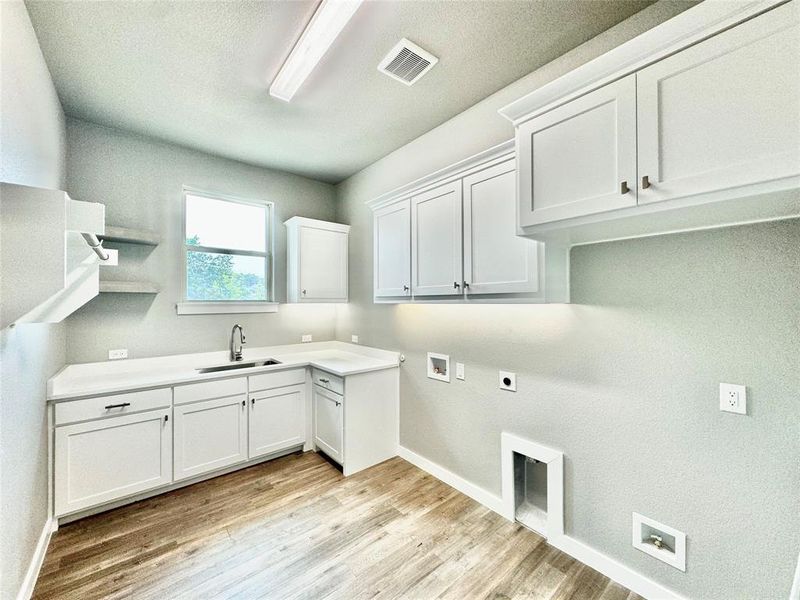 Laundry area featuring hookup for a washing machine, cabinets, light hardwood / wood-style floors, sink, and hookup for an electric dryer