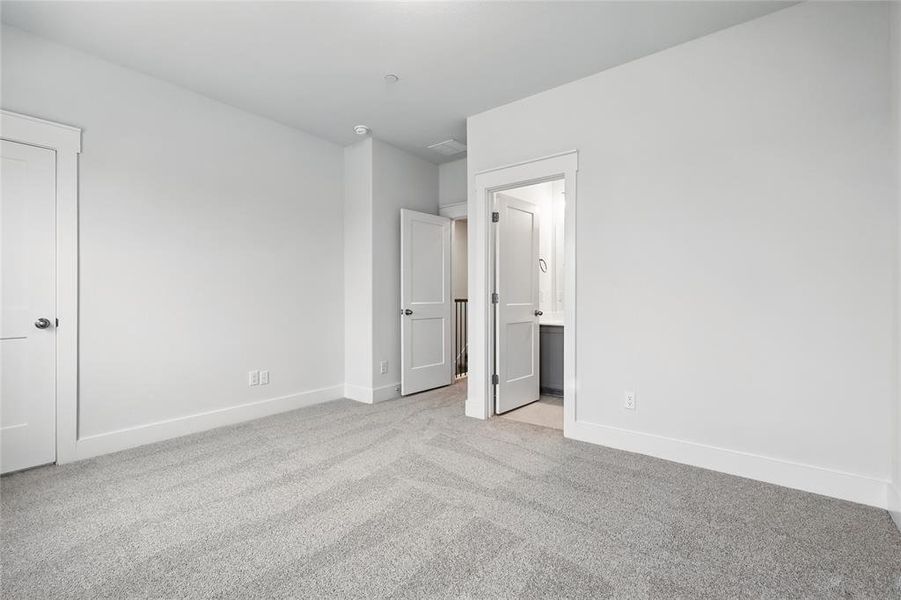 Unfurnished bedroom with light colored carpet and ensuite bathroom