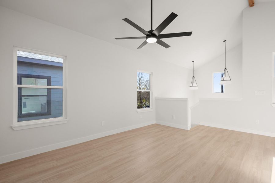Empty room with light wood finished floors, lofted ceiling, and ceiling fan