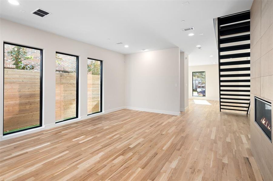 Empty room with plenty of natural light, a large fireplace, and light hardwood / wood-style flooring