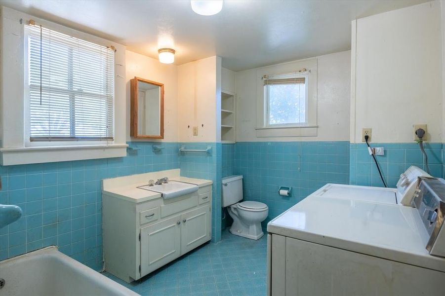 Bathroom featuring vanity, tile walls, toilet, and tile patterned flooring