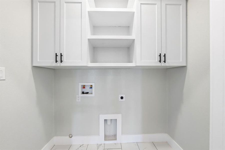 Laundry area with cabinet space, hookup for a washing machine, electric dryer hookup, and marble finish flooring