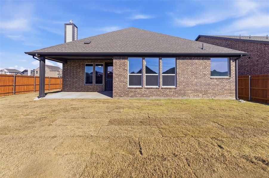 Rear view of house with roof with shingles, a patio, a fenced backyard, brick siding, and a chimney
