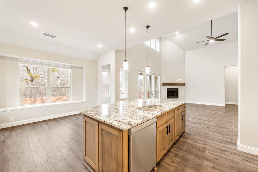 Kitchen island with granite countertop and sink, open to living area with fireplace and hardwood floors Kitchen island with granite countertop and sink, open to living area with fireplace and hardwood floors