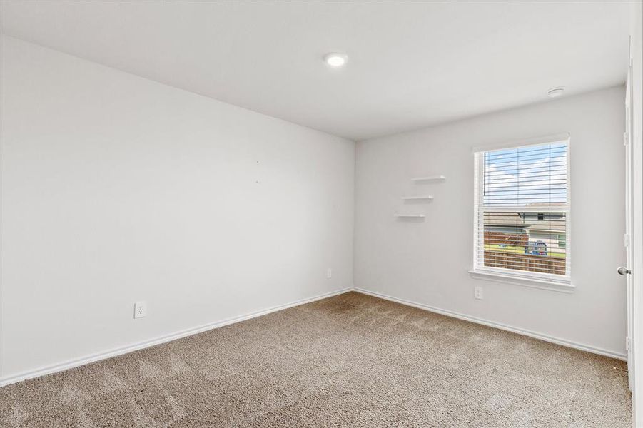 Well-lit room featuring carpet flooring, white walls, and a window with blinds