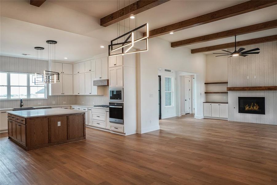 Kitchen featuring a center island, hanging light fixtures, ceiling fan, white cabinetry, and light wood-type flooring