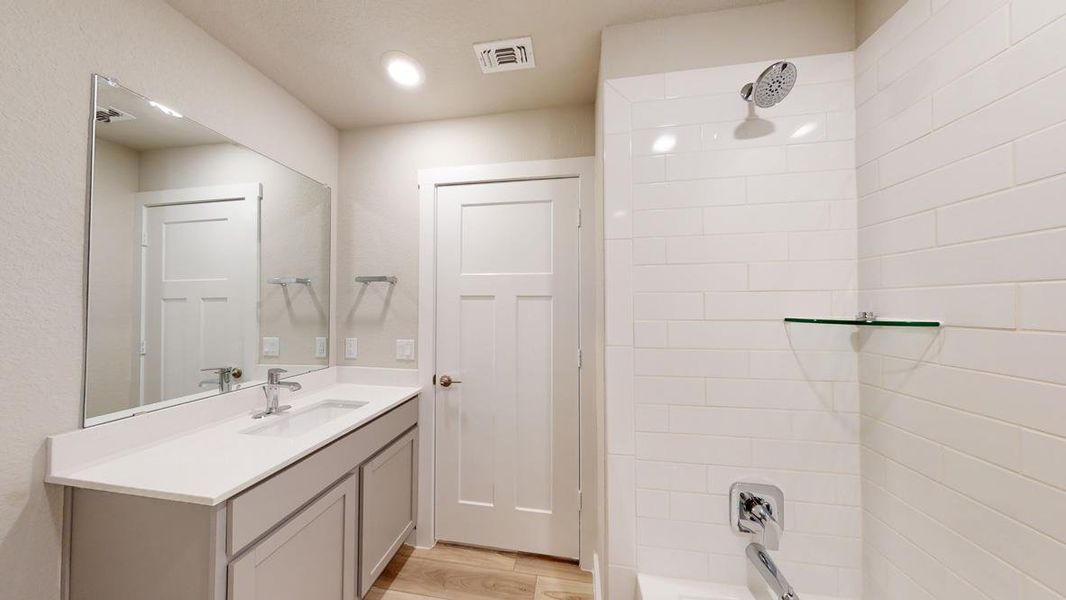 Bathroom with vanity, light wood-style flooring, and tub / shower combination