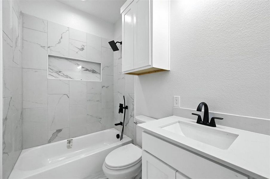 Full bathroom featuring tub / shower combination, vanity, and a textured wall