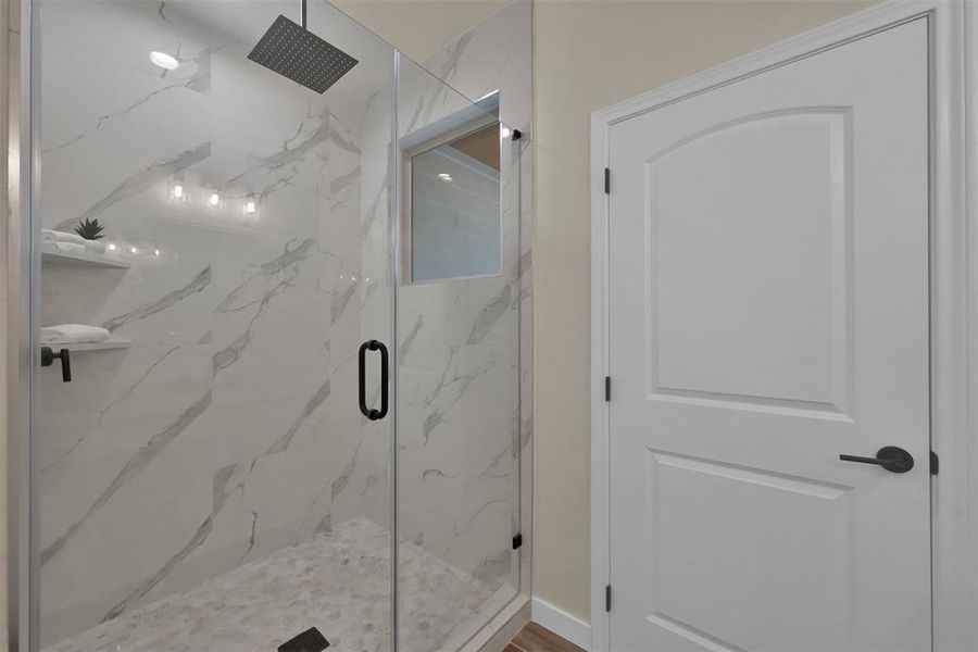 The full walk in shower has seamless glass surround, shelves for storage and a rain shower head.