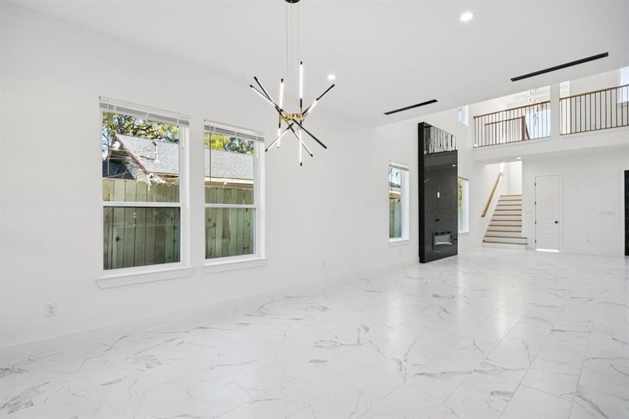 Unfurnished dining area with healthy amount of natural light, marble finish floors, recessed lighting, and a chandelier