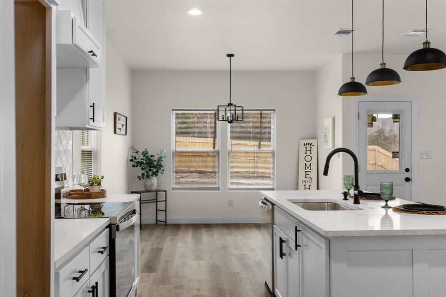 Kitchen with pendant lighting, white cabinetry, sink, a kitchen island with sink, and stainless steel appliances