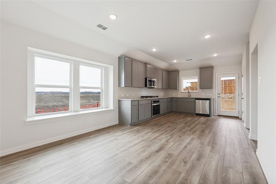 Kitchen with gray cabinets, light countertops, light wood-style floors, stainless steel appliances, and recessed lighting
