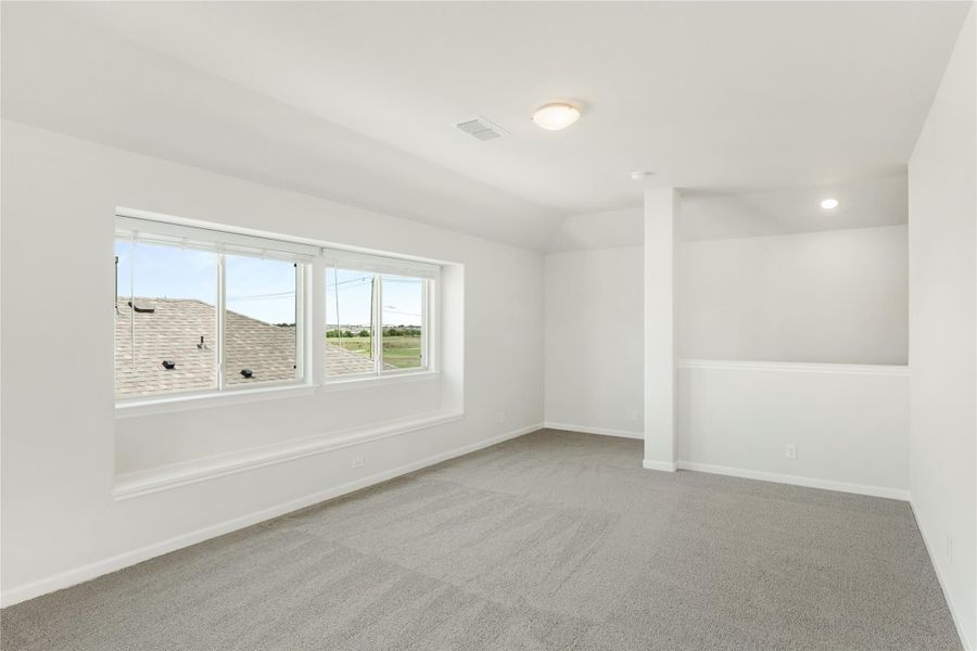 Empty room with gray carpet, white walls, large window, and a decorative column divider