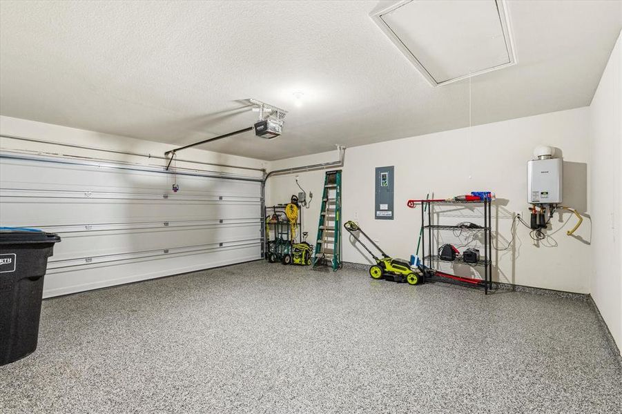 Garage featuring a durable floor covering with a warranty, and a view of the tankless water heater.