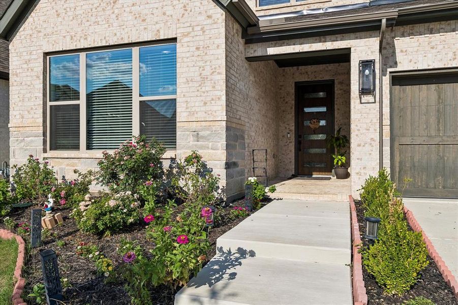Brick exterior with stone accents and a contemporary dark wood entry door featuring horizontal glass panels Brick exterior with stone accents and a contemporary dark wood entry door featuring horizontal glass panels