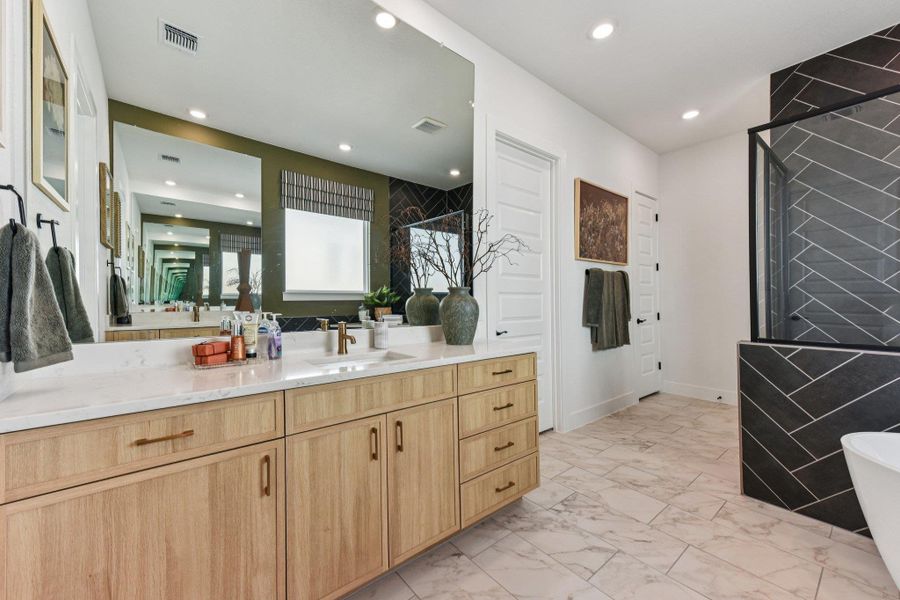 Herringbone wall tile and light wood vanities elevate this modern, light-filled bathroom design.