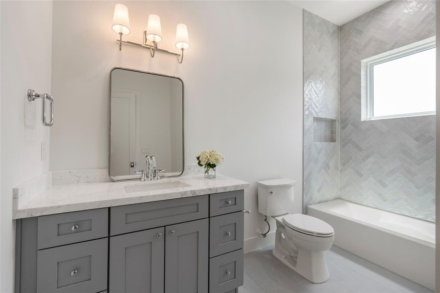 Secondary bathroom featuring quality cabinetry, generous counter space, and elegant fixtures.