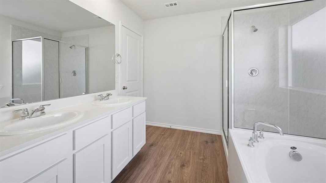 Full bath with double vanity, a bath, dark wood-style flooring, and a shower stall Full bath with double vanity, a bath, dark wood-style flooring, and a shower stall