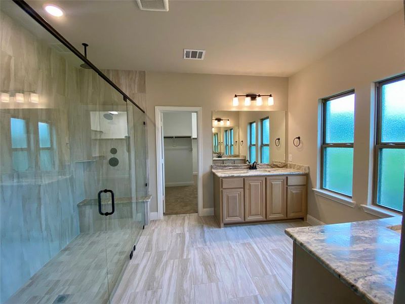 Spa-like master bath offers Fantasy Brown granite, Champagne cabinets, ORB fixtures, and 12x24 light grey tile