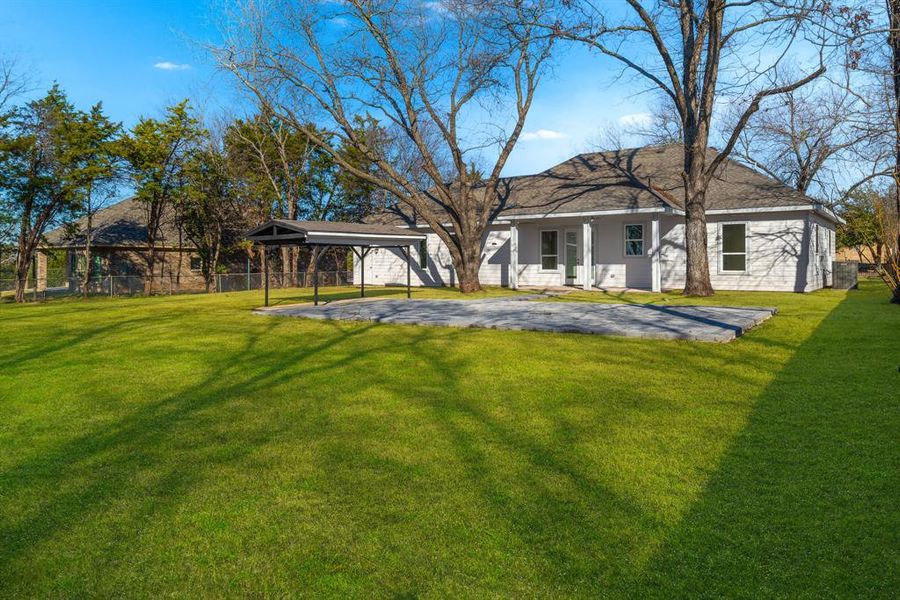 Rear view of house featuring a garage, a lawn, and a carport