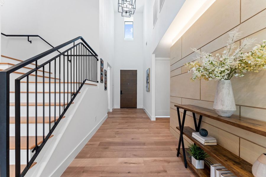 A two-story foyer, clean modern railings, and architectural lighting frame your welcome home.