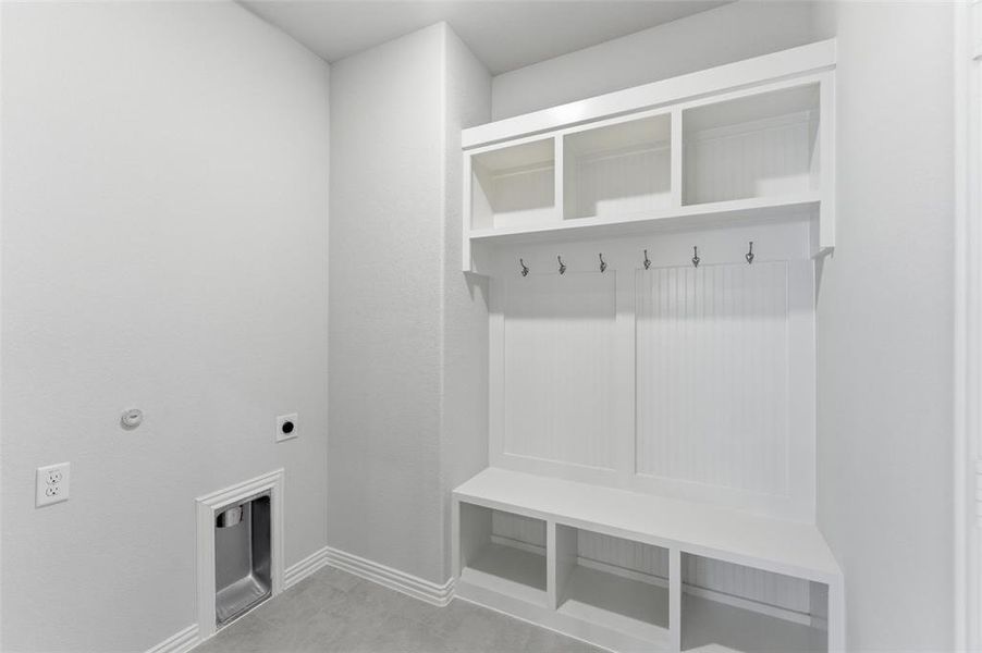 Laundry area featuring a built-in white mudroom bench with open shelving, integrated coat hooks, and beadboard paneling