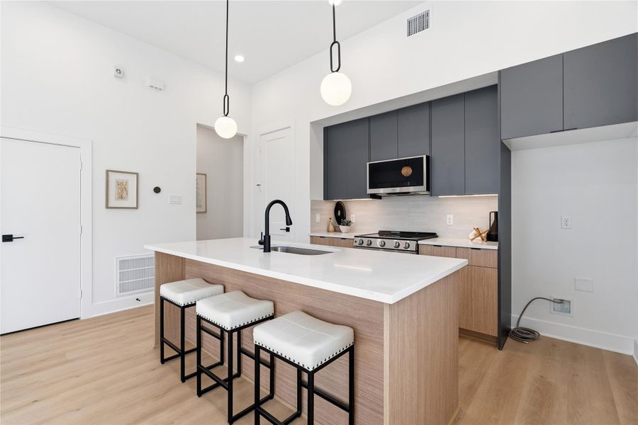 Contemporary duplex kitchen with quartz countertops, stainless appliances, and open sightlines to the living area.