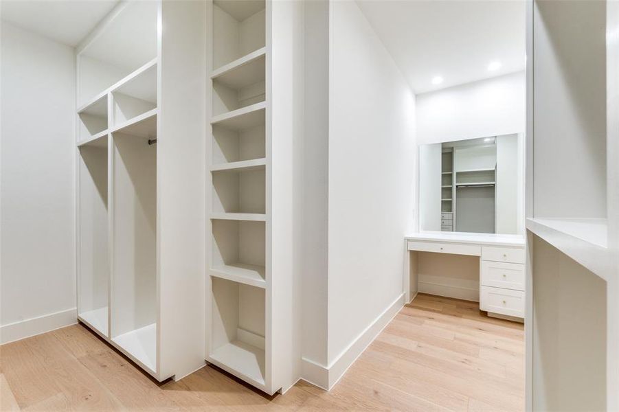 Walk in closet featuring built in desk and light hardwood / wood-style flooring