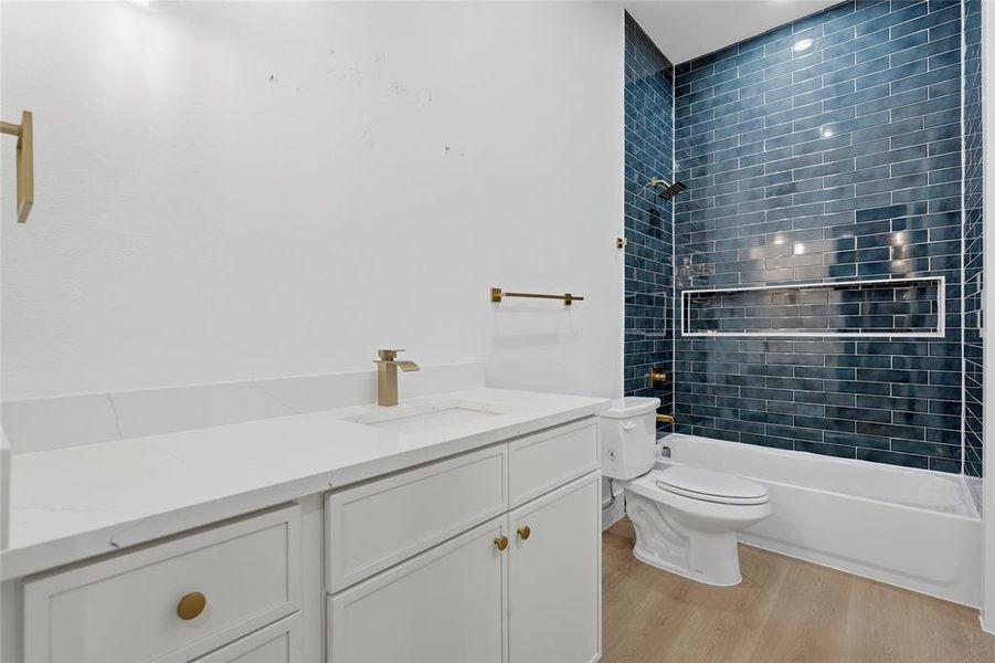 Bathroom featuring a white vanity with gold hardware, a white countertop, and a built-in sink Bathroom featuring a white vanity with gold hardware, a white countertop, and a built-in sink