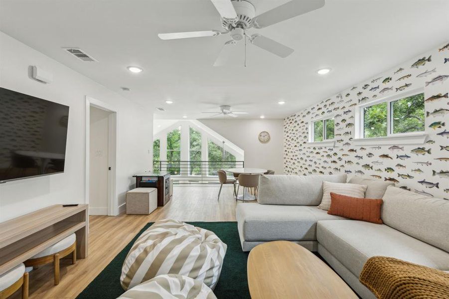 Living room with a wealth of natural light, light wood-type flooring, and ceiling fan
