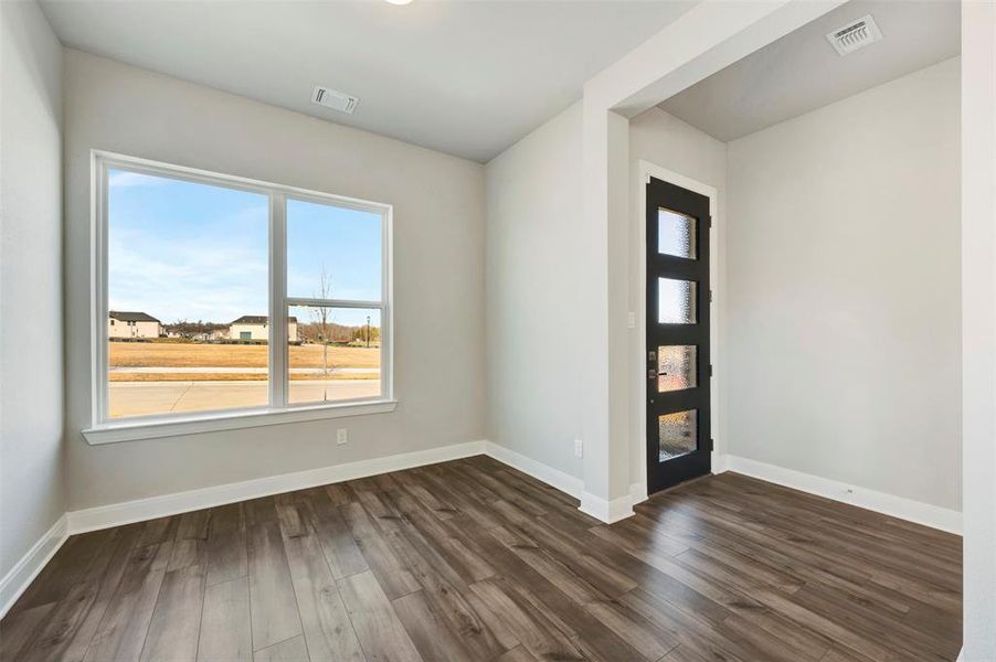 Empty room with dark wood-type flooring and baseboards