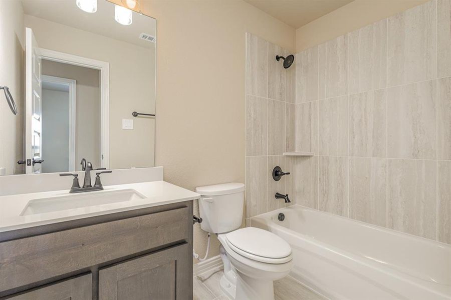 Full bathroom with toilet, tiled shower / bath, and vanity