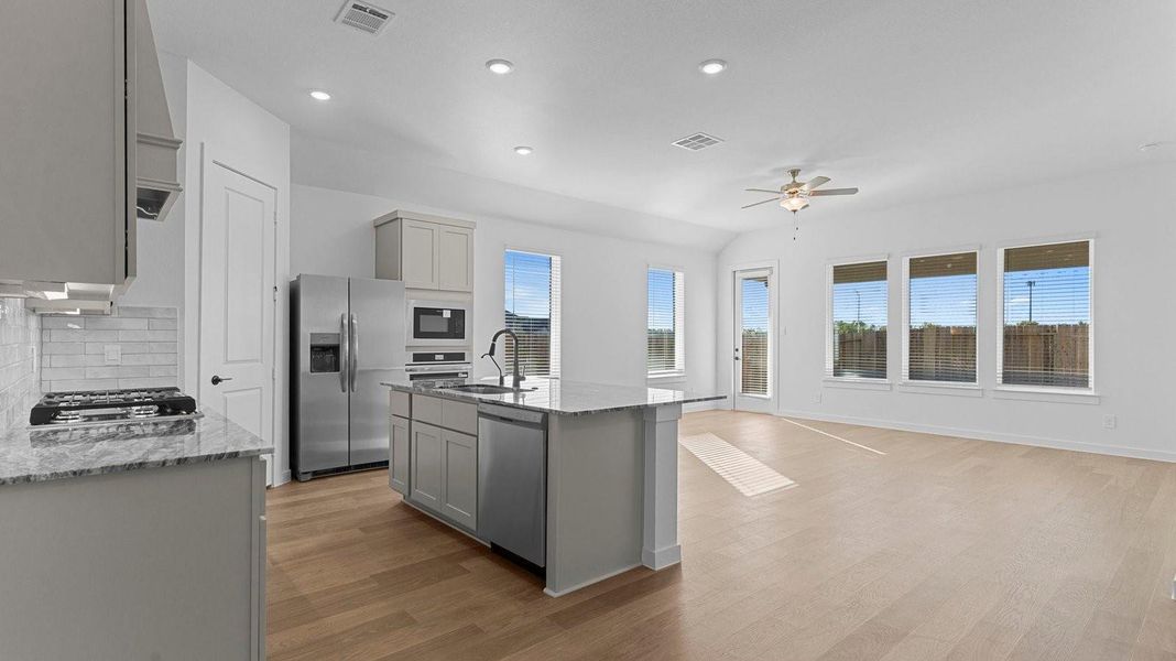 Bright and spacious kitchen with quartz countertops, stainless steel appliances, and an island with bar seating.