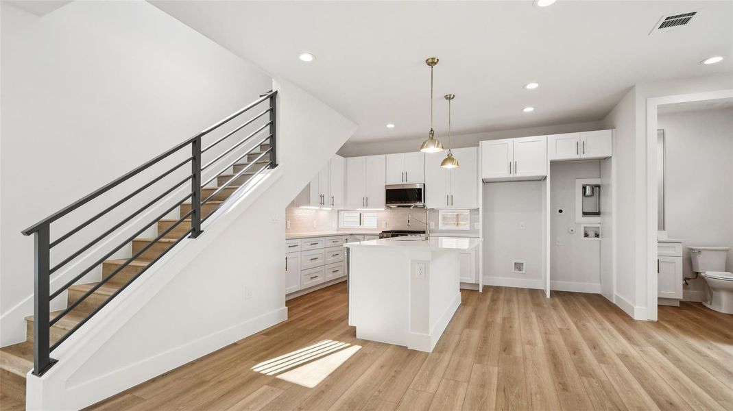 Kitchen featuring white cabinetry, pendant lighting, a kitchen island, recessed lighting, and light wood finished floors Kitchen featuring white cabinetry, pendant lighting, a kitchen island, recessed lighting, and light wood finished floors