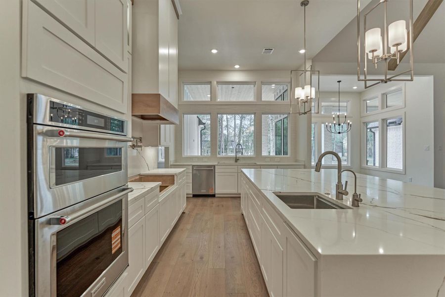 Bright, spacious kitchen with double ovens, sleek quartz countertops, and expansive windows that fill the space with natural light and stunning outdoor views.