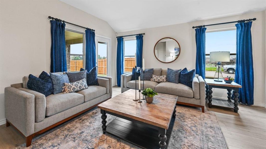 Living room featuring light wood finished floors and vaulted ceiling Living room featuring light wood finished floors and vaulted ceiling