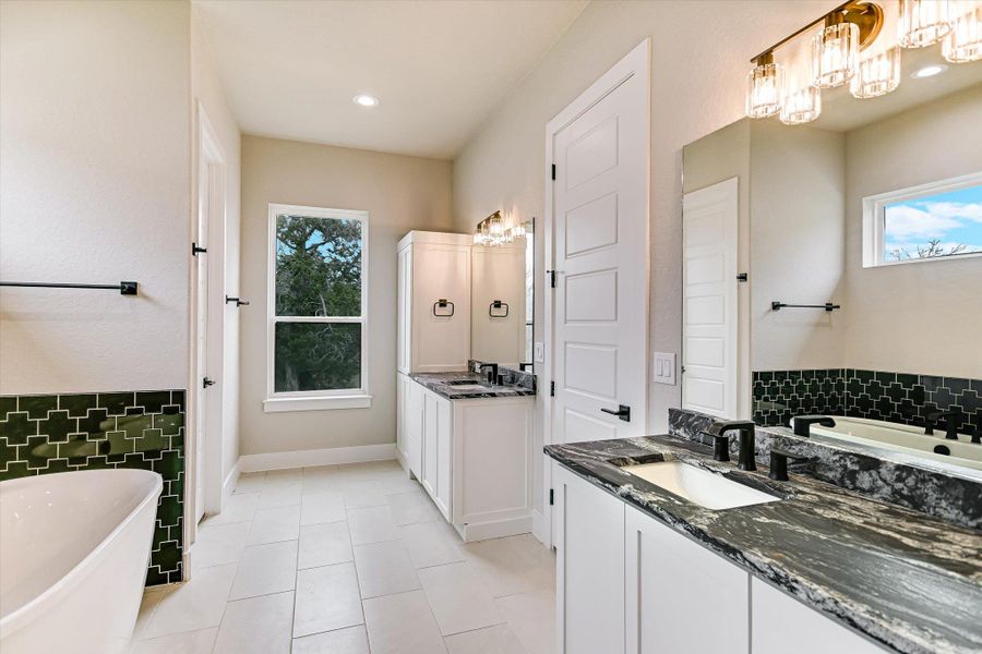 Full bathroom featuring a soaking tub, two vanities, and light tile patterned flooring