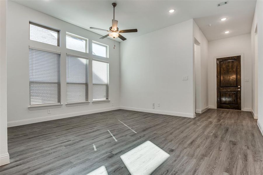 Living room with luxury vinyl plank flooring, ceiling fan, and a towering ceiling with modern canned lighting and lots of natural light