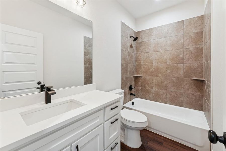 Full bathroom with dark wood finished floors, vanity, and  shower combination