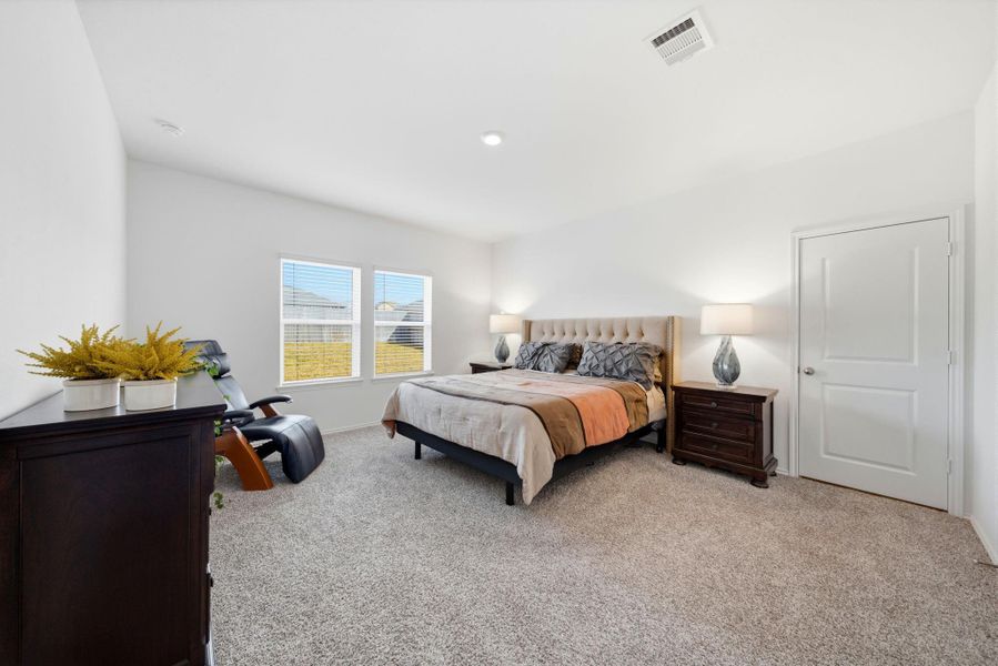 Spacious first-floor primary suite with ensuite bath, two closets, recessed lighting, and plush neutral carpet for serene retreat living.