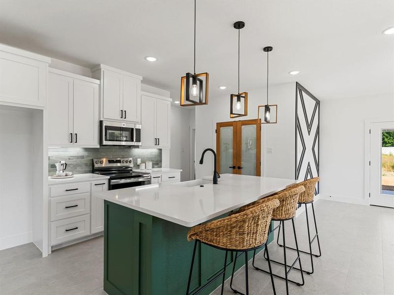 Kitchen featuring green cabinets, white cabinets, decorative backsplash, a kitchen breakfast bar, and stainless steel appliances