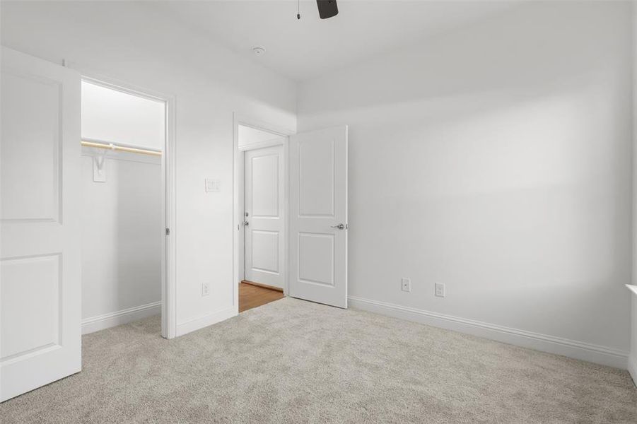 Unfurnished bedroom featuring ceiling fan, a closet, and light carpet